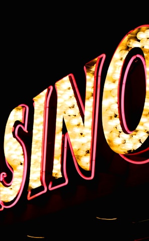 Brightly illuminated letters spell out 'CASINO' with glowing yellow bulbs and red outlines against a dark background.